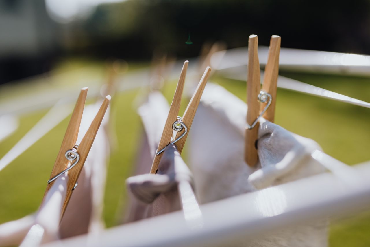 Wooden clothespins with wet underwear drying on metal collapsible clotheshorse on green meadow