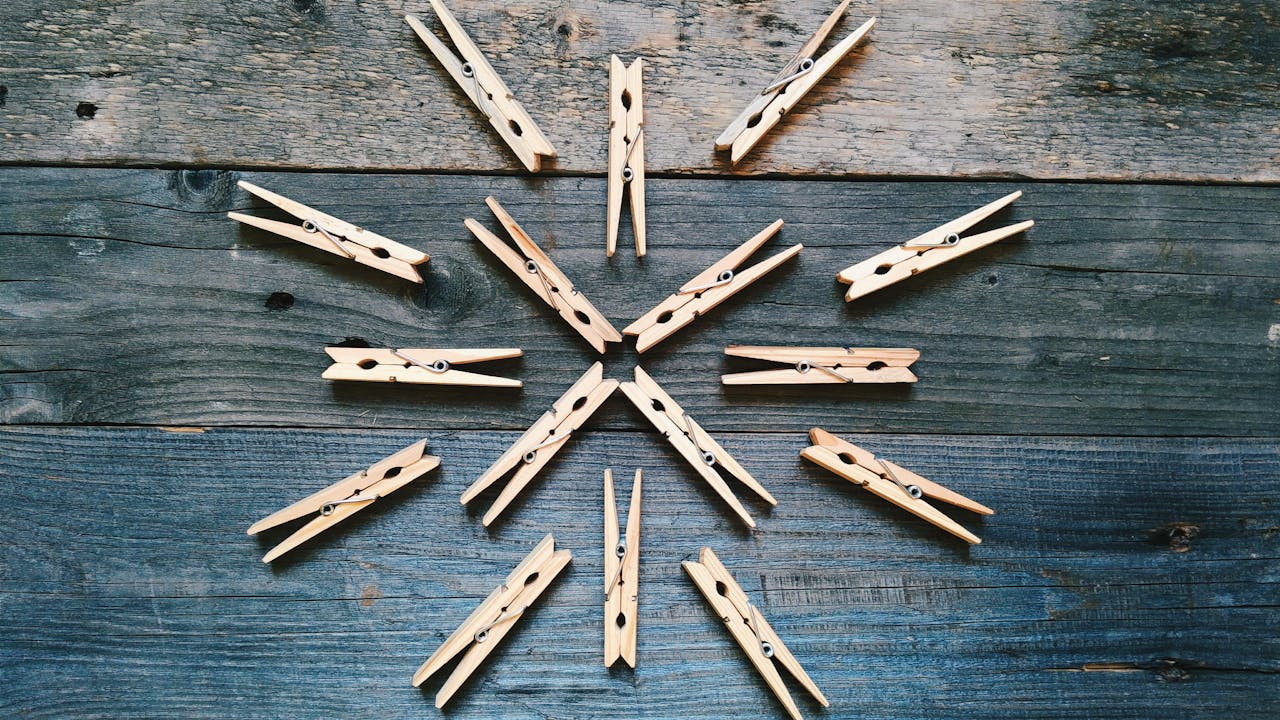 Creative pattern of wooden clothespins on a rustic wooden surface featuring a radial design.
